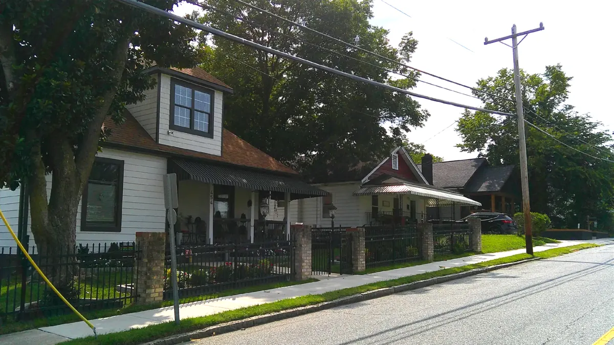 A renovated house behind a black iron fence in the neighborhood
