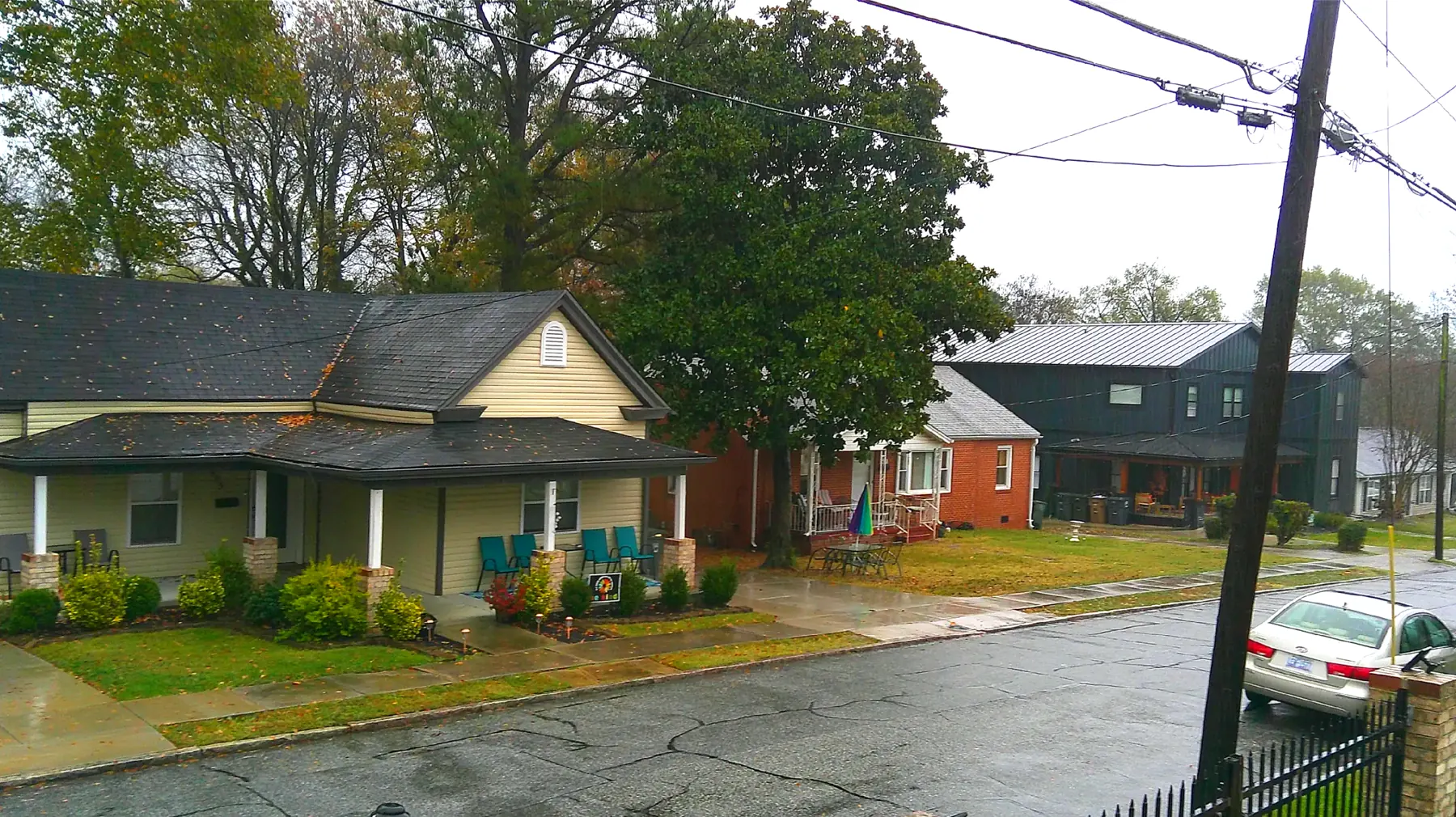 A renovated yellow house with a covered porch beside a quiet street