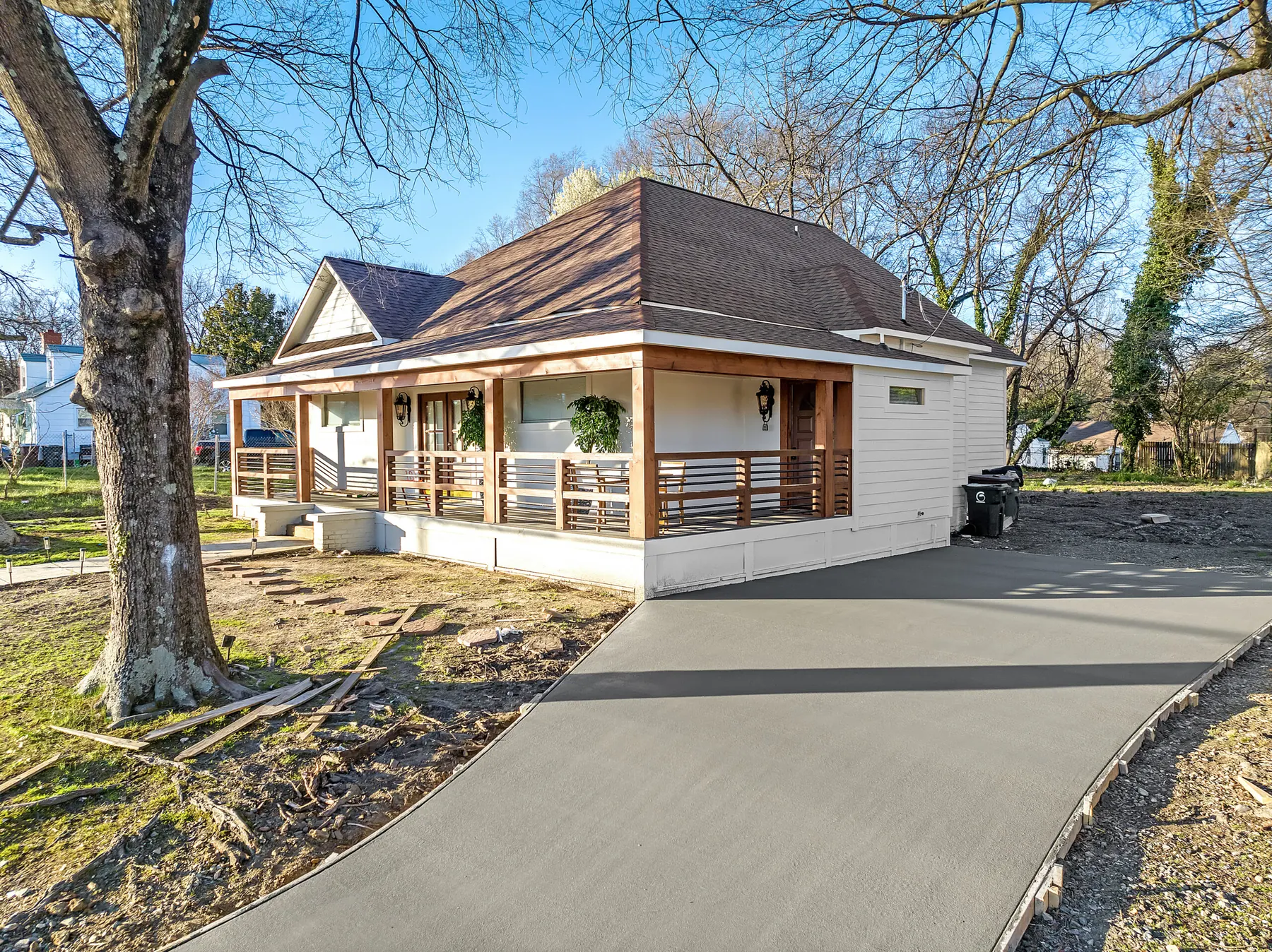 A newly poured concrete driveway leading to a renovated house with a porch